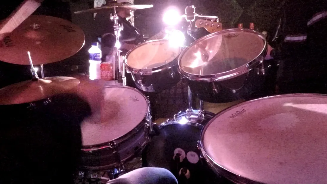 Bateria vista de cima durante um show, com pratos e luz forte